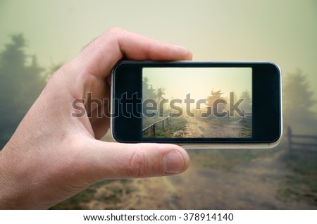 man holding a smartphone and photographed mountain landscape, photographed on a smartphone, selfie phone