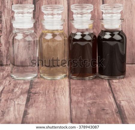 Vinegar, balsamic vinegar, maple vinegar and apple vinegar in glass vial over wooden background