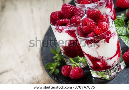 Vanilla ice cream with raspberries and mint dessert served in glasses on dark background, selective focus