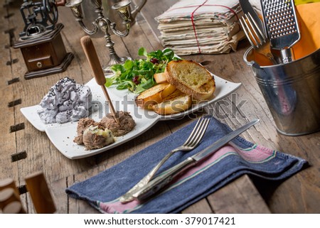 Tasty appetizers with chicken liver pate, blueberry mousse, valerian salad with sunflower seeds and toasted bread, on an old wooden table