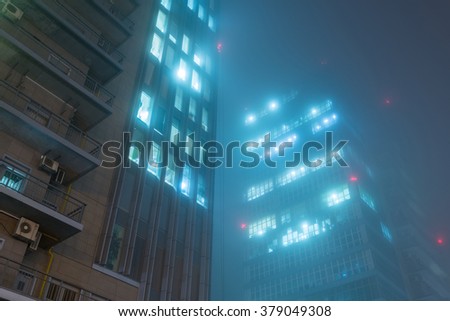 Skyscraper in fog with glowing windows at night