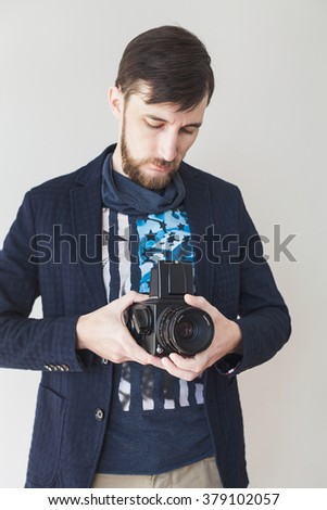 Indoor portrait of bearded young man with old medium format camera