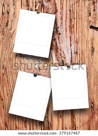 Close-up of three square photo frames with pins on weathered wood background