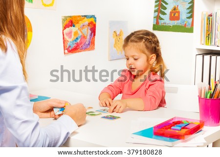 Little girl taking cards from table in the class