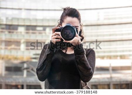 Pretty girl holding a camera and focusing
