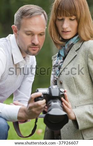 couple holding photo camera and watching pictures