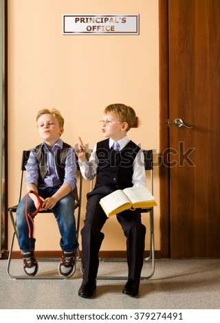 Two schoolboys are sitting next to principal's office. They are twin, but they have different each other behavior and clothes. For creating this picture were used two image of one and the same boy.