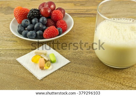 Super foods, anti-oxidant supplements and a cup of soy milk on wooden table Royalty-Free Stock Photo #379296103