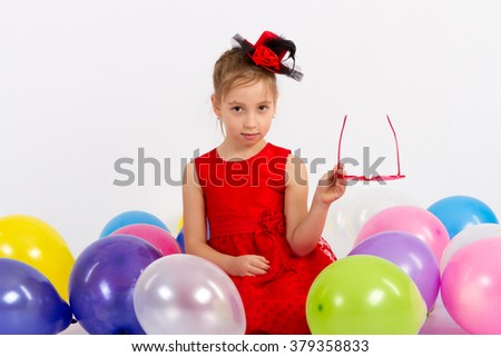 girl in red dress sits with balls and holding glasses on white background