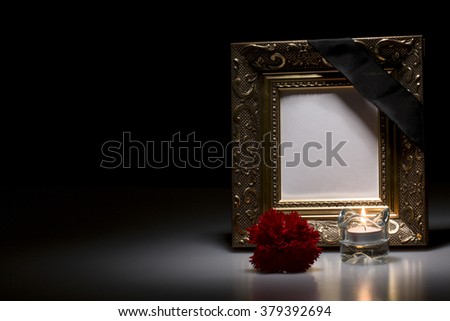 blank golden mourning frame with flower and candle on dark background