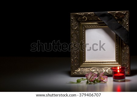 blank golden mourning frame with flower and candle on dark background