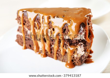 Piece of chocolate cake with caramel in white saucer close up