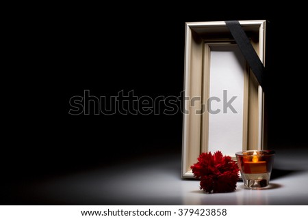 blank mourning frame with flower and candle on dark background