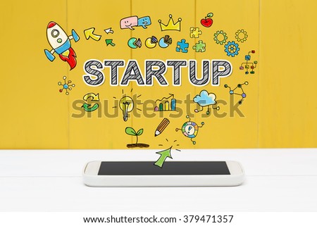 Start Up concept with smartphone on yellow wooden background