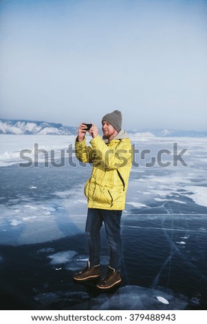 bearded man in a bright jacket photographed standing on the ice of the frozen lake Baikal