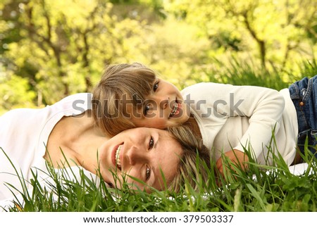 Mom and her little daughter lie on the grass