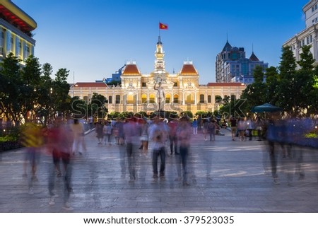 People are walking and taking pictures in front of the City Hall building, Ho Chi Minh City, Vietnam.