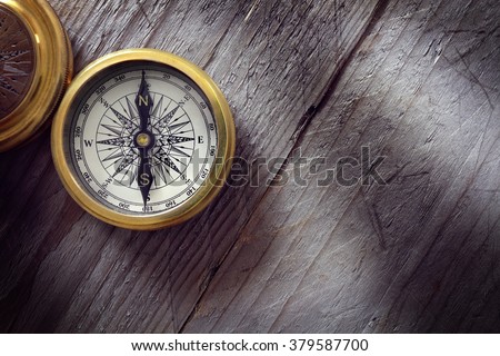 Antique golden compass on wood background concept for direction, travel, guidance or assistance Royalty-Free Stock Photo #379587700