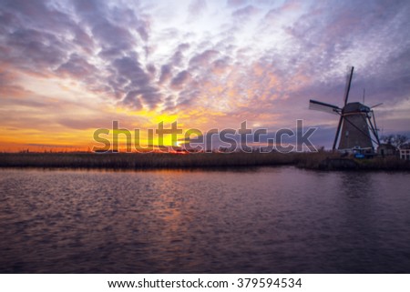 Windmills and water canal on sunset in Kinderdijk, Holland. Blurred photo as background.
