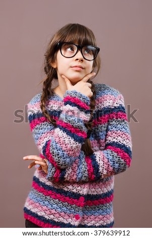 Little nerdy girl is thinking about something.Little nerdy girl thinking