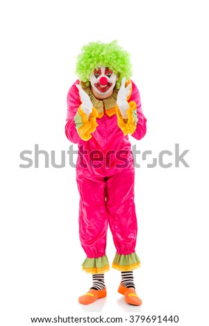 Portrait of a funny playful clown in green wig showing showing emotions, looking at camera and smiling, isolated on a white background