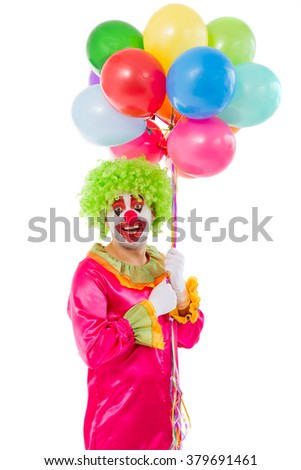 Portrait of a funny playful clown in green wig holding balloons, looking at camera and smiling, isolated on a white background