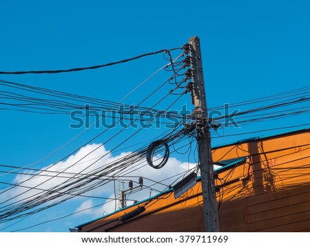 Electricity wire and pole with building on blue sky background