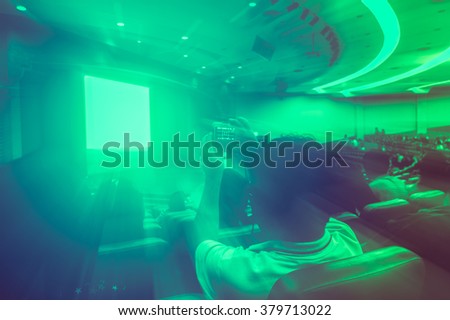 Picture in zoom effect of man with digital camera recording movie lighting in the theater.