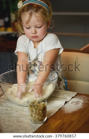 beautiful little girl learns to cook in the kitchen