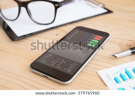 phone and business stock application on work desk Royalty-Free Stock Photo #379765960