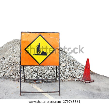 An orange color luminous man at work signage with a pile of gravel and red safety cone.
