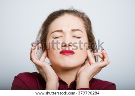 Pretty girl covering her ears isolated on a gray background
