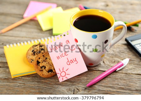Piece of note paper with cup of coffee and cookies on grey wooden background