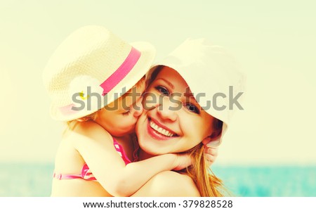 happy family on the beach. baby daughter kissing mother  at sea