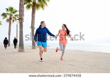 Happy smiling couple over palm trees beach background. Running lovers on vacation
