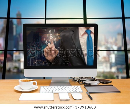 Workspace with computer desktop with Businessman point sign of money at the screen on the trading graph over the blurred photo of cityscape background,Elements of this image furnished by NASA