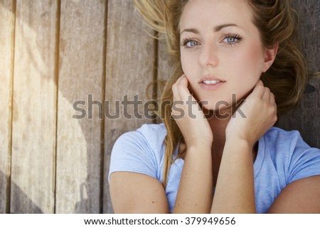 Closely image of a young gorgeous woman with beautiful blue eyes posing while lying on a wooden background with copy space, attractive Sweden female looking at camera, feminine beauty concept