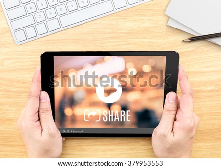 Hand holding tablet with Video sharing on screen on wood table ,Internet marketing concept. Royalty-Free Stock Photo #379953553