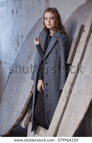 A fashionable woman in a black dress and grey spring coat.
