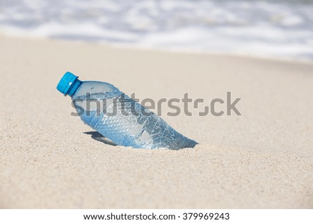 Plastic bottle of water in sand on tropical sandy beach