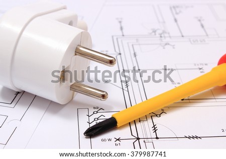 Screwdriver, work tools and electric plug lying on construction drawing of house, accessories for engineering work, energy concept