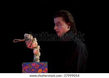 Surprised vampire with gift box taking out garlic, isolated on black background