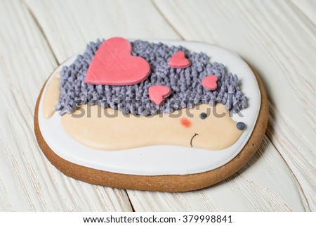 Gingerbread heart cookies with a picture of a hedgehog on a wooden white background