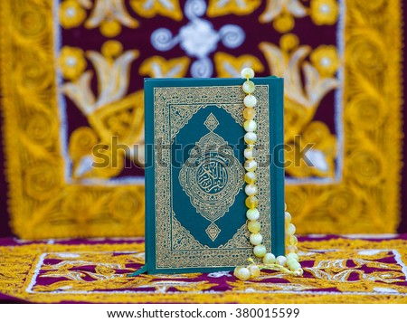 
holy book the Koran and prayer beads on a bright background . In the book written in Arabic letters the name of the book " Quran " Royalty-Free Stock Photo #380015599