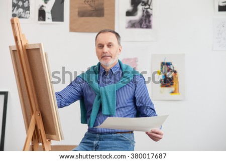 Skillful mature artist is working in his studio
