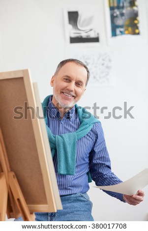 Cheerful senior painter is drawing the image
