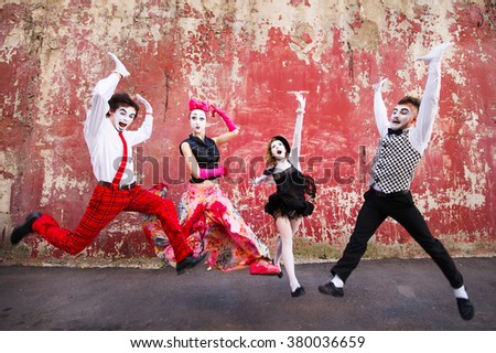 Four mimes jumping on a background of a red wall. Royalty-Free Stock Photo #380036659