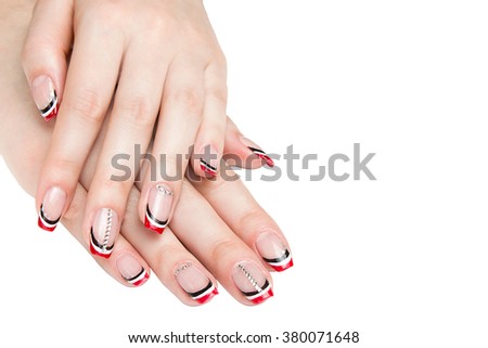 French manicure - beautiful manicured female hands with red black and white manicure with rhinestones isolated on white background