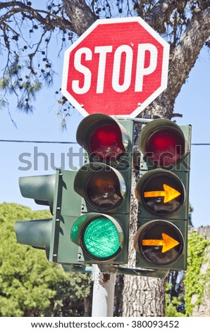 Road sign "stop" and traffic lights at the crossroads on sunny day with two orange pointers