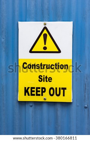white and yellow construction site keep out sign on blue
